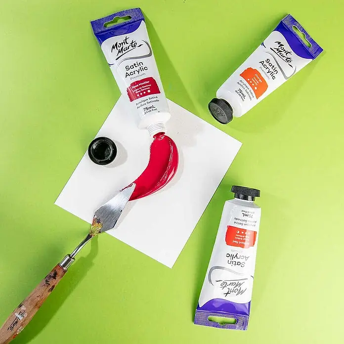 Mont Marte Acrylfarbe Premium - Rosenrot, 75 ml, Tube - Drei Mont Marte Satin Acrylfarbtuben, eine rote Farbe auf Papier mit einem Spachtel aufgetragen.