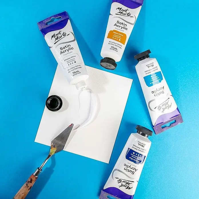 Mont Marte Acrylfarbe Premium - Chinesisch Weiß, 75 ml, Tube - Vier Mont Marte Satin Acryl Premium Farb-Tuben (75ml) in verschiedenen Farben, mit weißer Farbe auf Papier und einem Spachtel.