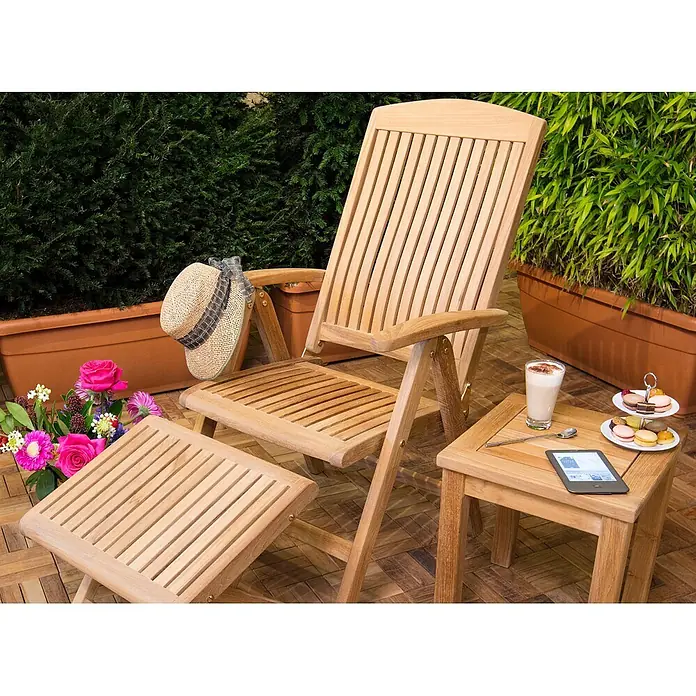 Kai Wiechmann Gartenhocker - Teakholz, Höhenverstellbar, braun - Naturholz-Terrassenstuhl mit Fußstütze und Beistelltisch auf einer Holzterrasse, bereit zum Entspannen mit Getränk und E-Reader.