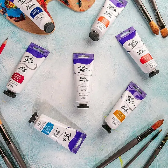 Mont Marte Acrylfarbe Premium - Chinesisch Weiß, 75 ml, Tube - Mont Marte Satin Acrylfarben in weißen Tuben mit lila Kappen und verschiedenen Farben, zusammen mit Pinseln und Palette ausgestellt.