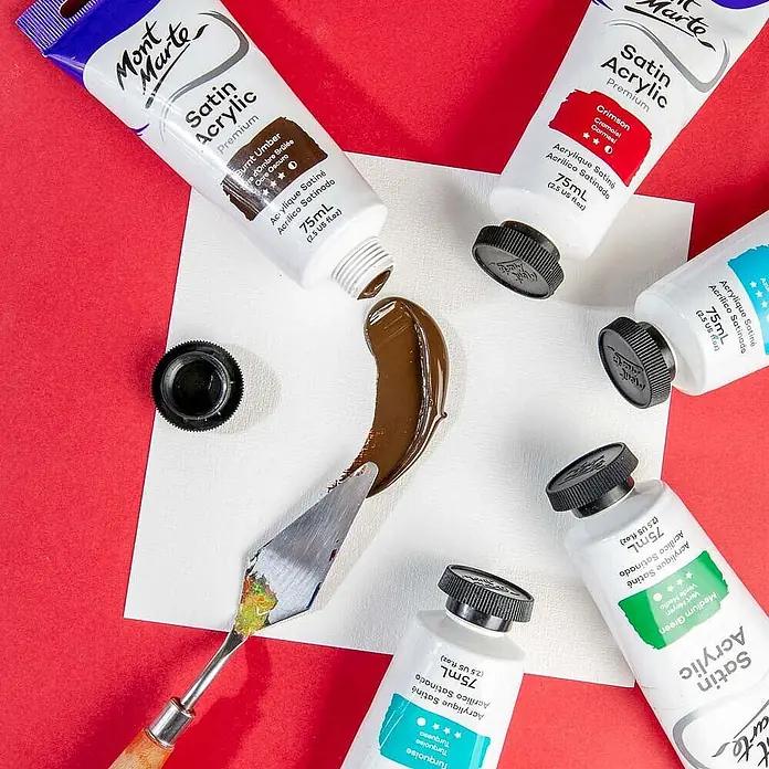 Mont Marte Acrylfarbe Premium - Gebrannte Umbra, 75 ml, Tube - Tuben Mont Marte Satin Acrylfarbe, darunter Umbra gebrannt, auf eine weiße Fläche gepresst und mit einem Spachtel verteilt.
