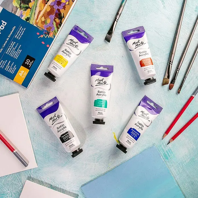 Mont Marte Acrylfarbe Premium - Viridiangrün, 75 ml, Tube - Mont Marte Satin Acrylfarben in verschiedenen Farbtönen, Pinsel, Bleistifte und ein Zeichenblock auf hellblauem Untergrund.