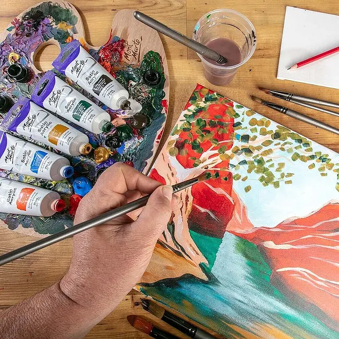Mont Marte Acrylfarbe Premium - Hookers Grün, 75 ml, Tube - Mont Marte Satin Acrylfarben in Tuben auf einer Palette, von einer Hand zum Malen einer Landschaft auf einer Leinwand verwendet.