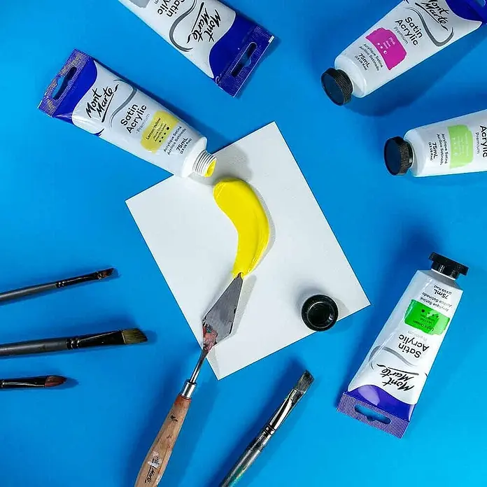 Mont Marte Acrylfarbe Premium - Zitronengelb, 75 ml, Tube - Mont Marte Satin Acrylfarben in Tuben, mit zitronengelber Farbe auf weißem Papier, einem Spachtel und Pinseln.