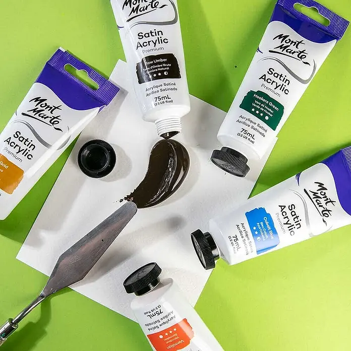Mont Marte Acrylfarbe Premium - Natürliche Umbra, 75 ml, Tube - Fünf Mont Marte Satin Acrylfarben-Tuben in verschiedenen Farben mit herausgedrückter Umbra und einem Spachtel.