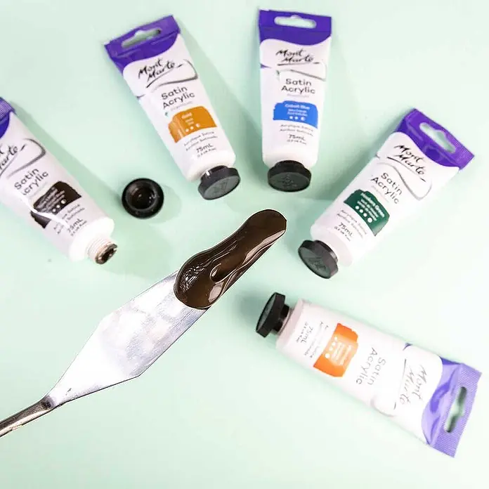 Mont Marte Acrylfarbe Premium - Natürliche Umbra, 75 ml, Tube - Fünf Tuben Mont Marte Satin Acrylfarbe in verschiedenen Farben, eine offen mit dunkelbrauner Farbe auf einem Spachtel.