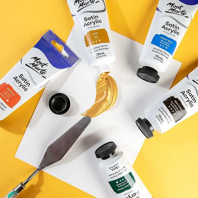 Mont Marte Acrylfarbe Premium - Gold, 75 ml, Tube - Verschiedene Mont Marte Satin Acrylfarben-Tuben mit Goldfarbe und Spachtel auf Papier.