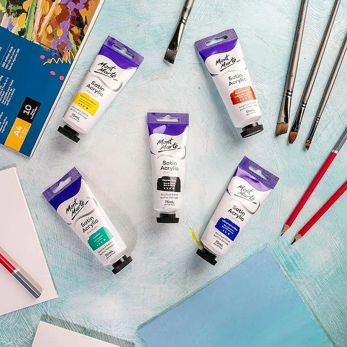 Mont Marte Acrylfarbe Premium - Paynesgrau, 75 ml, Tube - Fünf Tuben Mont Marte Satin Acrylfarbe in verschiedenen Farben, umgeben von Pinseln und Kunstzubehör.
