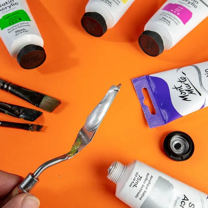 Mont Marte Acrylfarbe Premium - Silber, 75 ml, Tube - Acrylfarbtuben, Pinsel und ein Spachtel mit silberner Farbe, bereit für die Kunst.