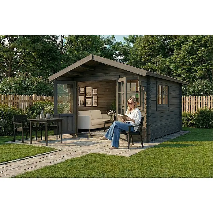 Alpholz Gartenhaus Gabriel 300 x 400 cm - Außenmaß inkl. Dachüberstand (B x T): 338 x 467 cm, Holz, Grau - Gartenhaus aus dunklem Holz mit Terrasse, eine Frau liest entspannt ein Buch.