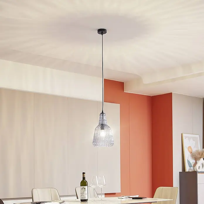 Lindby Pendelleuchte Belarion - L x B x H: 23 x 23 x 35 cm, alu / grau / zink, rauchgrau, E27 - Eine Pendelleuchte aus klarem, gemustertem Glas hängt über einem Esstisch und erhellt den Raum warm.