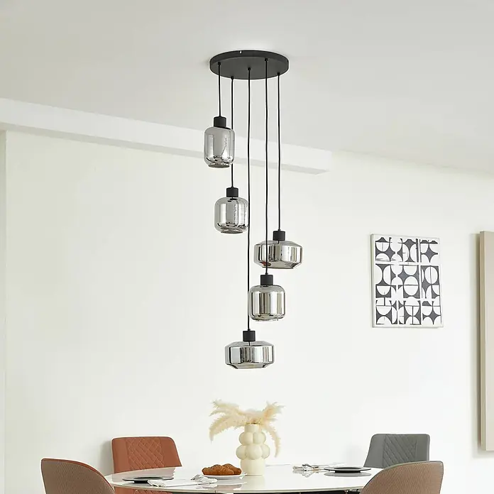 Lindby Pendelleuchte in rauchgrau transparent, schwarz matt, Hängelampe -  - Schwarze Deckenplatte mit fünf Pendelleuchten aus Rauchglas, hängen in unterschiedlichen Höhen über einem Esstisch.