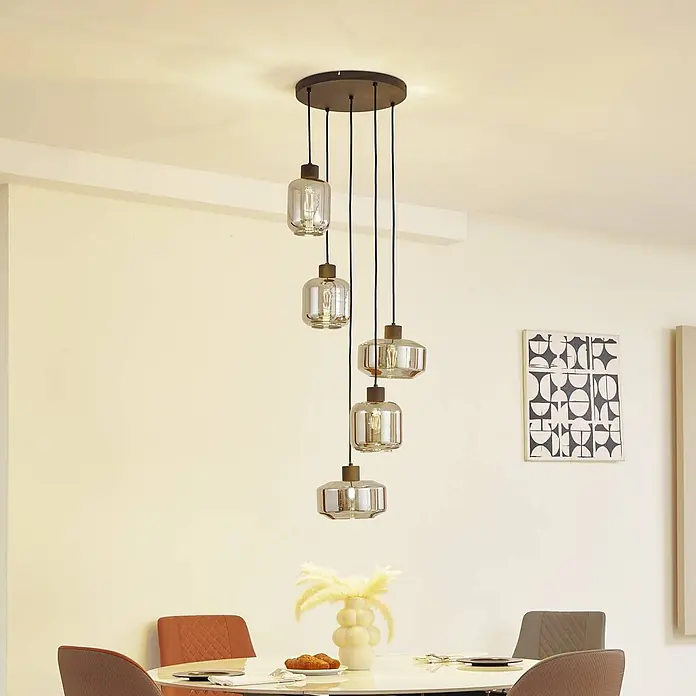 Lindby Pendelleuchte in rauchgrau transparent, schwarz matt, Hängelampe -  - Fünfflammige Pendelleuchte mit rauchfarbenen Glasschirmen und dunkelbrauner Baldachin, die einen Essbereich beleuchtet.