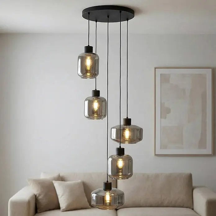 Lindby Pendelleuchte in rauchgrau transparent, schwarz matt, Hängelampe -  - Fünfflammige Pendelleuchte mit Rauchglas-Schirmen und schwarzen Armaturen, elegant über einem Sofa hängend.