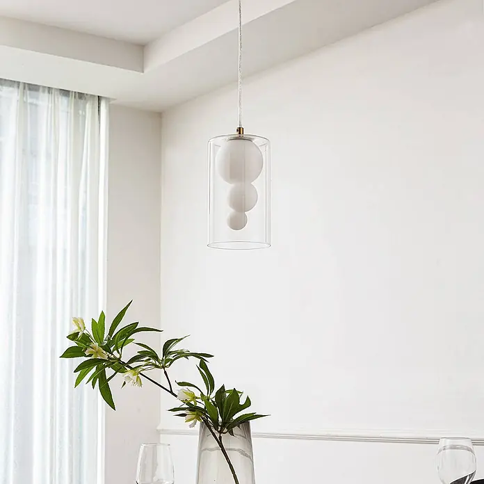 Lindby Pendelleuchte Kupla - L x B x H: 12 x 12 x 20 cm, klar / transparent, transparent, weiß, G9 - Moderne Pendelleuchte: klarer zylindrischer Glasschirm mit drei gestapelten weißen Kugeldiffusoren, in hellem Raum.