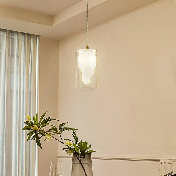 Lindby Pendelleuchte Kupla - L x B x H: 12 x 12 x 20 cm, klar / transparent, transparent, weiß, G9 - Moderne Glas-Pendelleuchte mit weißen Kugeln innen, goldener Akzent, hängt in einem Raum.