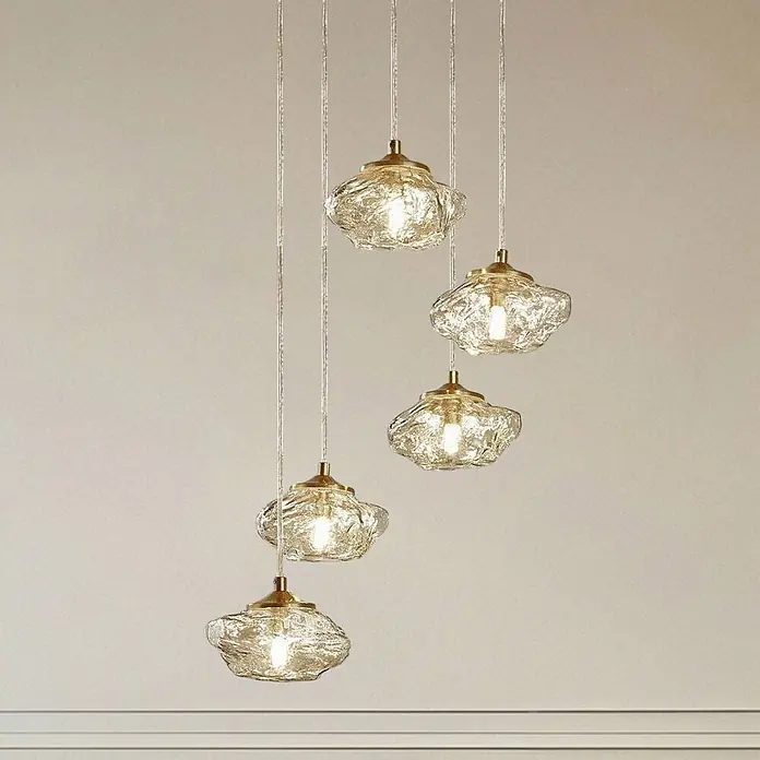 Lindby Pendelleuchte Piatra - L x B x H: 44,5 x 44,5 x 150 cm, creme / amber, amber, messing, G9 - Fünf Pendelleuchten mit strukturierten Klarglasschirmen und messingfarbenen Beschlägen hängen in verschiedenen Höhen.