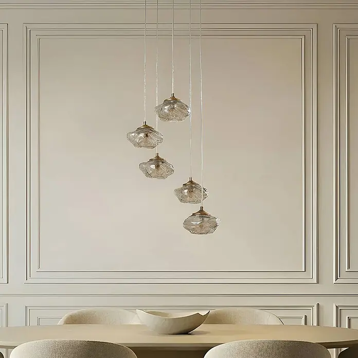 Lindby Pendelleuchte Piatra - L x B x H: 44,5 x 44,5 x 150 cm, creme / amber, amber, messing, G9 - Fünf Pendelleuchten mit gewellten Klarglasschirmen und Messingakzenten hängen in verschiedenen Höhen über einem Esstisch.