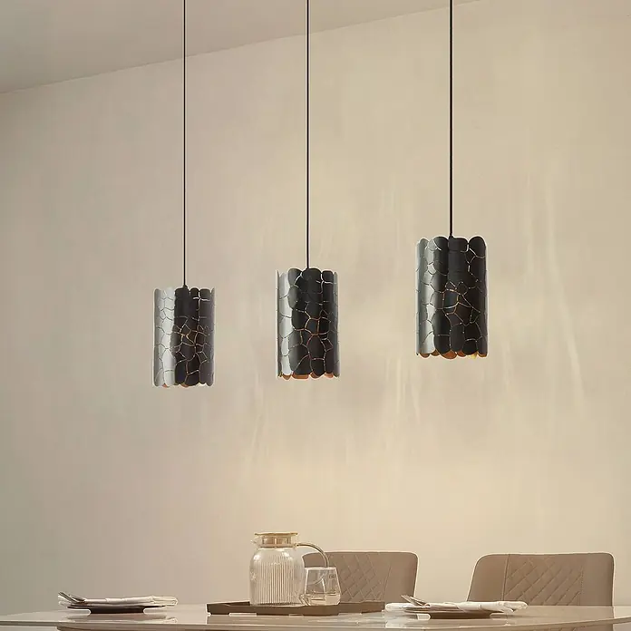 Lindby Pendelleuchte Aralena - L x B x H: 92 x 15 x 25 cm, schwarz, Schwarz, gold, E27 - Drei schwarze Pendelleuchten mit goldfarbenem Rissmuster innen beleuchten einen Esstisch.