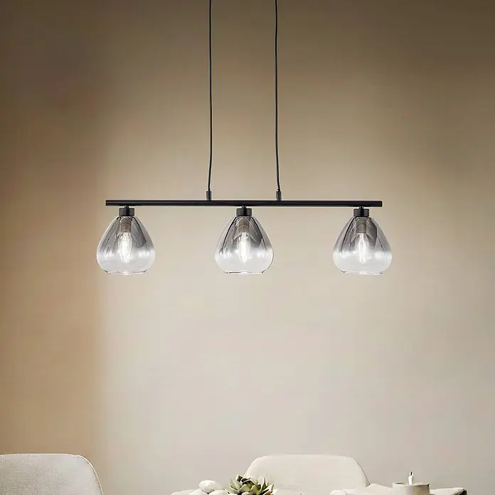 Lindby Pendelleuchte Pendura - L x B x H: 75 x 15 x 15 cm, alu / grau / zink, rauchgrau, Schwarz matt, E14 - Schwarze 3-flammige lineare Pendelleuchte mit klaren Glasschirmen, über einem Tisch hängend.