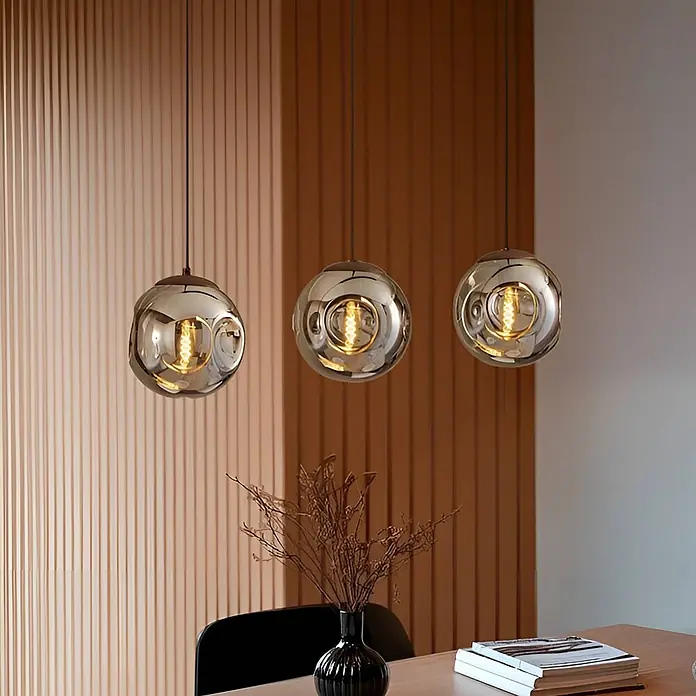 Lindby Pendelleuchte Valentina - L x B x H: 75 x 18 x 150 cm, alu / grau / zink, braun, rauchgrau, E14 - Drei kugelförmige Pendelleuchten mit getöntem Spiegelglas und leuchtenden Glühfäden hängen über einem Esstisch.