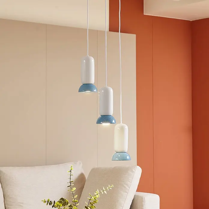 Lindby Pendelleuchte Kerimi - L x B x H: 30 x 30 x 21,5 cm, weiß / opal, weiß, Blau, GU10 - Drei moderne Pendelleuchten mit weißen zylindrischen Oberteilen und gesprenkelten blauen Kuppelunterteilen, hängen über einem Sofa im Wohnzimmer.