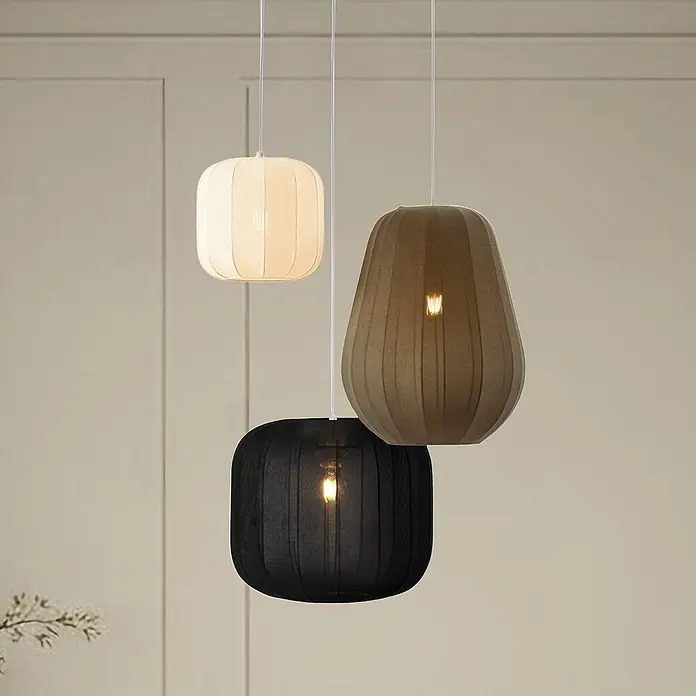 Lindby Pendelleuchte Helin - Multicolour, weiß, Schwarz, grau, E27 - Drei Hängelampen mit plissierten Stoffschirmen in Creme, Dunkelbraun und Schwarz, die den Raum beleuchten.