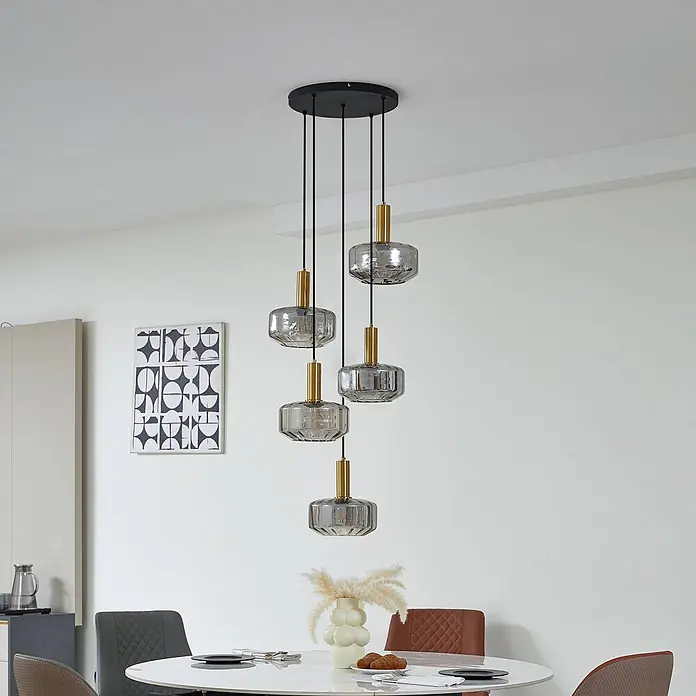 Lindby Pendelleuchte Hildur - L x B x H: 51,2 x 35 x 11,8 cm, alu / grau / zink, rauchgrau, messing, E27 - Fünfflammige Pendelleuchte mit schwarzem Sockel, goldenen Akzenten und gerippten rauchgrauen Glasschirmen, die einen Essbereich beleuchtet.