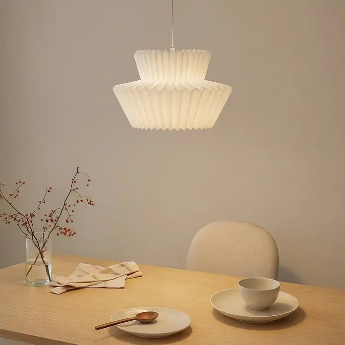 Lindby Pendelleuchte Magali - L x B x H: 45 x 45 x 25 cm, weiß / opal, weiß, E27 - Weiße gefaltete Papier-Pendelleuchte beleuchtet einen hellen Holztisch mit minimalistischer Dekoration.