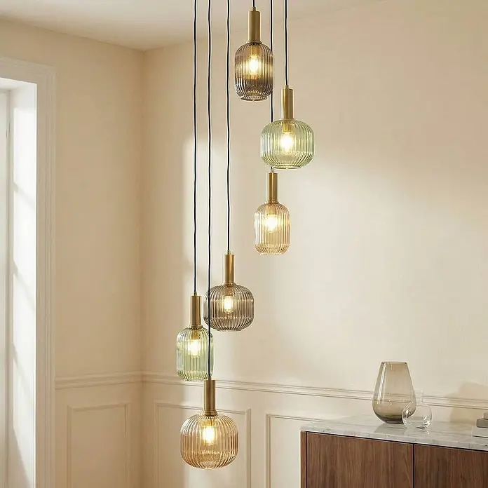 Lindby Pendelleuchte Doroteo - L x B x H: 52 x 52 x 18 cm, alu / grau / zink, rauchgrau, E27 - Eine Gruppe von geriffelten Pendelleuchten aus Glas in Bernstein- und Grüntönen mit Messingfassungen.