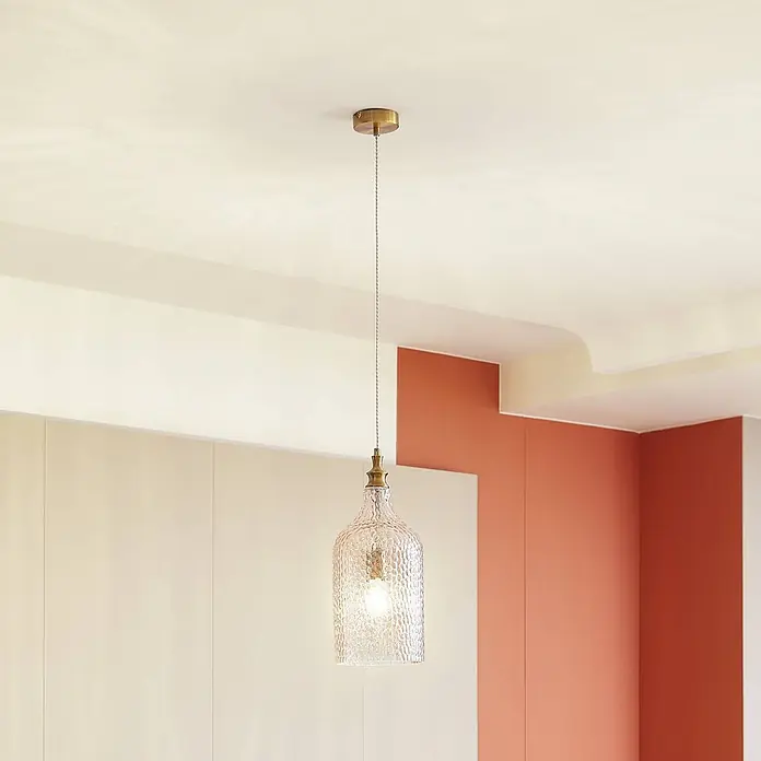 Lindby Pendelleuchte Drakar - creme / amber, amber, gold, E27 - Pendelleuchte mit einem gehämmerten Klarglasschirm und messingfarbenen Metalldetails, von der Decke hängend.