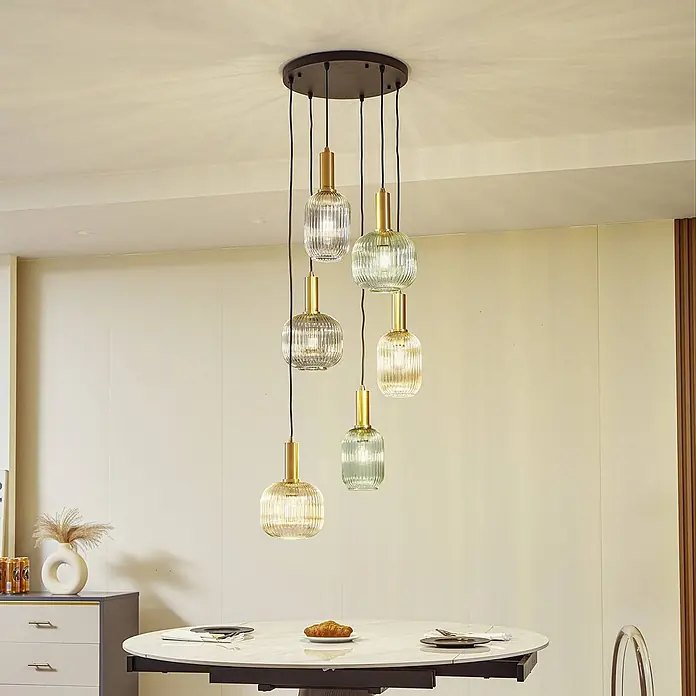 Lindby Pendelleuchte Doroteo - L x B x H: 52 x 52 x 18 cm, alu / grau / zink, rauchgrau, E27 - Kronleuchter aus sechs gerippten Glaspendelleuchten (klar und grün) mit Messingakzenten, über einem Esstisch hängend.