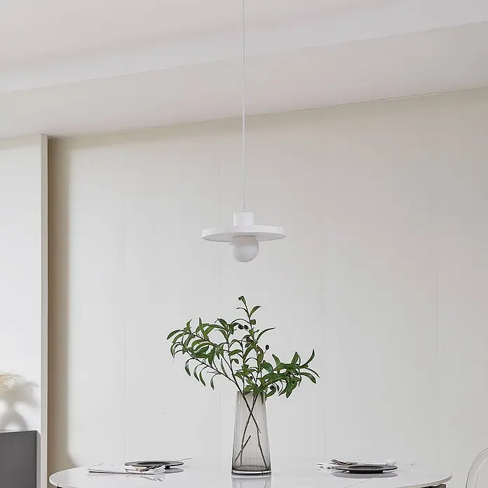 Lindby Pendelleuchte Nielson - weiß / opal, weiß, E27 - Weiße Pendelleuchte mit flachem Scheibenschirm und kugelförmiger Glühbirne über einem Tisch mit einem Vasenarrangement.