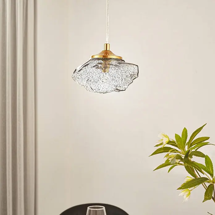 Lindby Pendelleuchte Piatra - L x B x H: 15,5 x 15,5 x 8,5 cm, schwarz, rauchgrau, messing, G9 - Eine moderne Pendelleuchte mit strukturiertem Klarglasschirm und messingfarbener Fassung, die von der Decke hängt.