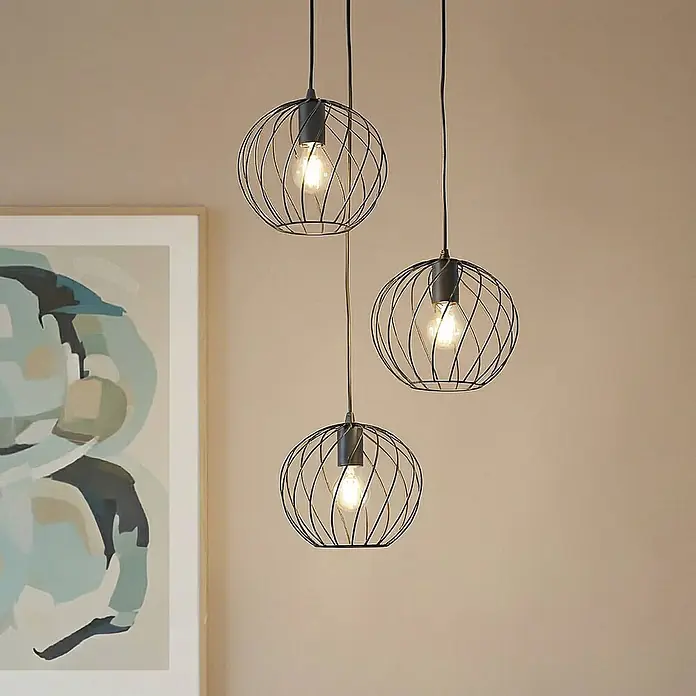 Lindby Pendelleuchte Danika - schwarz, Schwarz, E27 - Drei schwarze Drahtkugel-Pendelleuchten mit freiliegenden Vintage-Glühbirnen in einem modernen Interieur hängend.