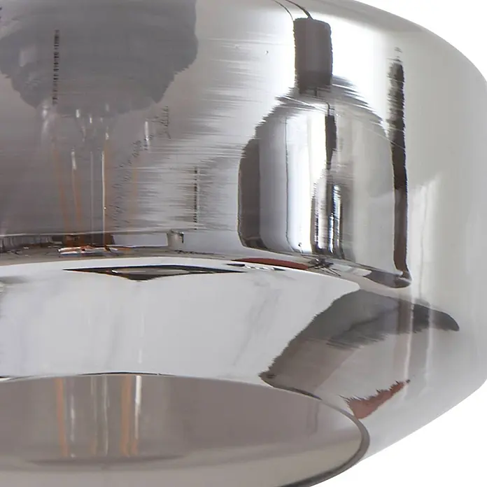 Lindby Pendelleuchte in rauchgrau transparent, schwarz matt, Hängelampe -  - Nahaufnahme eines reflektierenden silbernen Glasschirms mit sichtbarer Glühbirne.