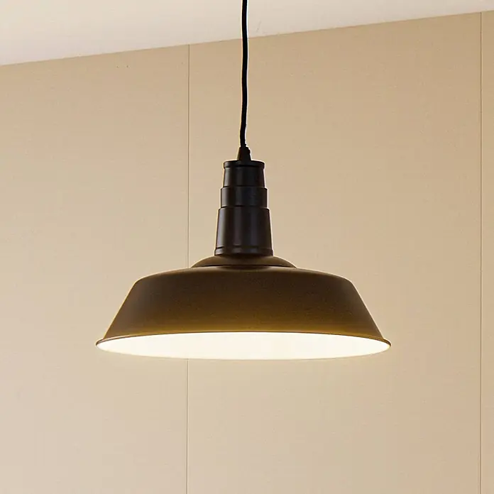 Lindby Pendelleuchte Laylan - schwarz, Schwarz, weiß, E27 - Eine schwarze Pendelleuchte im Industriestil mit breitem Schirm hängt beleuchtet vor einer hellbeigen Wand.