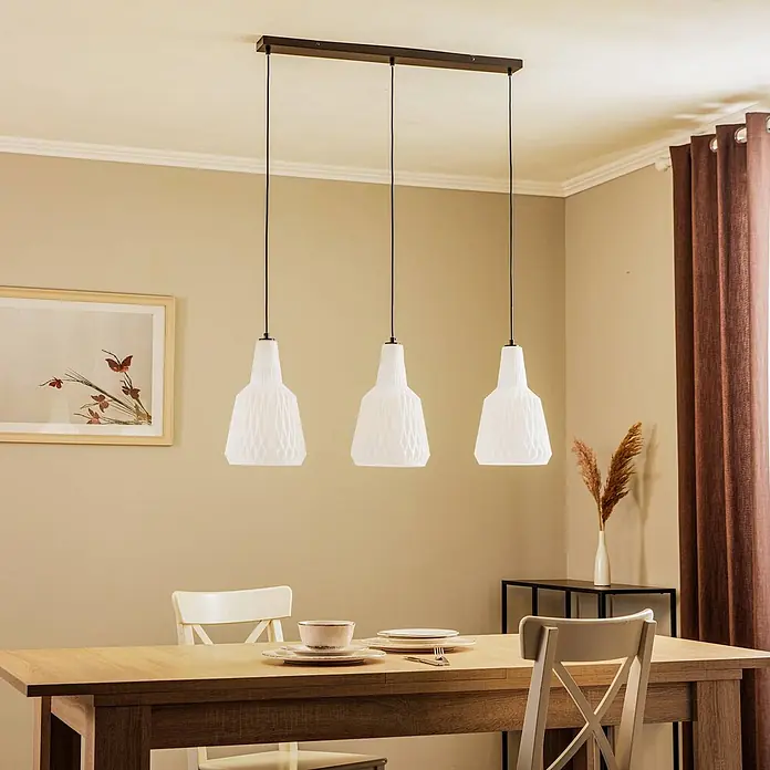 Lindby Pendelleuchte Belarion - L x B x H: 98 x 23 x 35 cm, weiß / opal, opal, E27 - Dreifach-Pendelleuchte mit dunkler Stange und drei weißen gemusterten Schirmen, über einem Esstisch hängend.