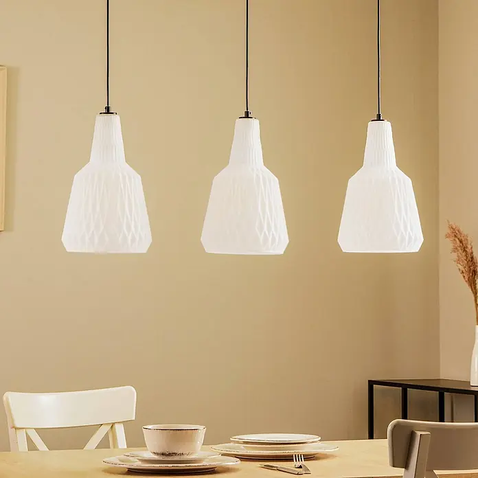 Lindby Pendelleuchte Belarion - L x B x H: 98 x 23 x 35 cm, weiß / opal, opal, E27 - Drei weiße Pendelleuchten mit geometrisch strukturierten Schirmen hängen über einem gedeckten Esstisch.