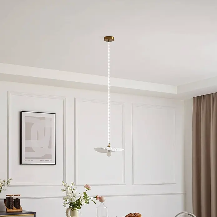 Lindby Pendelleuchte Annira - weiß / opal, weiß, messing, E14 - Weiße Pendelleuchte mit texturiertem Schirm, Messing-Deckenplatte und schwarzem Kabel, in einem Raum hängend.