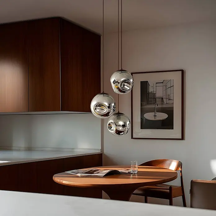 Lindby Pendelleuchte Valentina - alu / grau / zink, rauchgrau, kaffee, E27 - Drei kugelförmige Chrom-Pendelleuchten hängen über einem Holzesstisch in einem modernen Interieur.