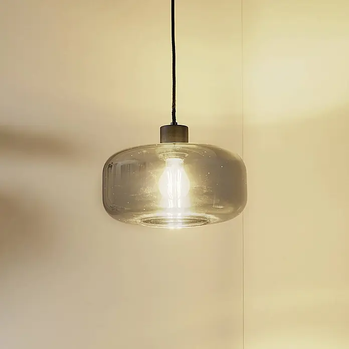 Lindby Pendelleuchte Hildur - L x B x H: 28,5 x 28,5 x 14,5 cm, alu / grau / zink, rauchgrau, sandSchwarz, E27 - Pendelleuchte aus rauchgrauem Glas mit beleuchteter Glühbirne an schwarzem Kabel.