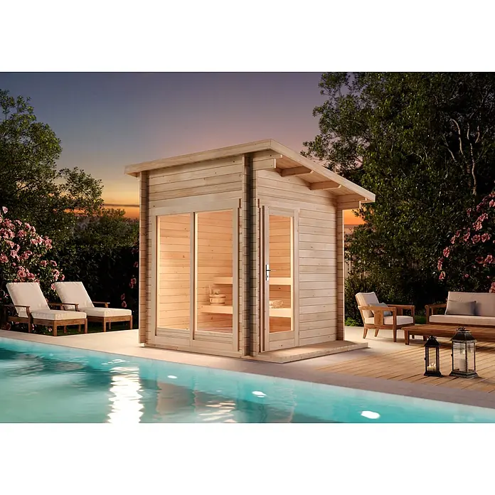 FinnTherm Saunahaus Lizzy XS 40mm Wandstärke -  - Einladende helle Außensauna aus Holz mit Glastüren, von innen beleuchtet, an einem ruhigen Pool bei Sonnenuntergang.