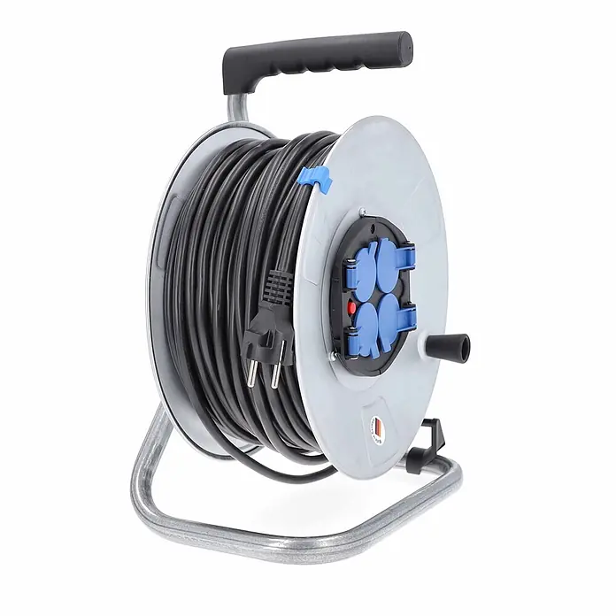 as - Schwabe Metallkabeltrommel 50m H05VV-F 3G1,5 IP20 -  - Grau-schwarze Kabeltrommel mit vier blauen Steckdosen, schwarzem Griff und silbernem Metallrahmen.