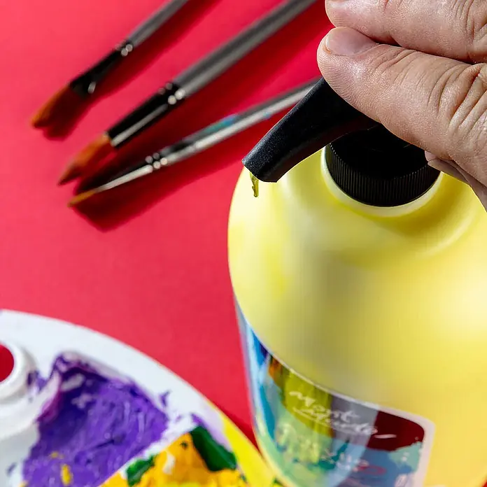 Mont Marte Acrylfarbe Signature - Zitronengelb, 2.000 ml, Flasche mit Tropfpipette - Hand drückt Pumpe auf gelber Farbflasche, Farbe tropft. Pinsel und Palette sind sichtbar.