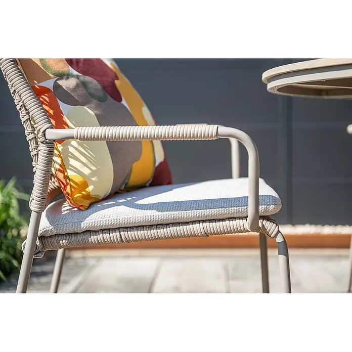 Garden Impressions Gartensessel Swifty - 1 Stk., Stahl, Polyester, Stapelbar, Taupe, B x T x H: 63,5 x 84,5 x 56,5 cm - Ein Outdoor-Sessel mit beigefarbenem Metallgestell, geflochtenen Seildetails, hellem Kissen und buntem Musterkissen in sonniger Outdoor-Umgebung.