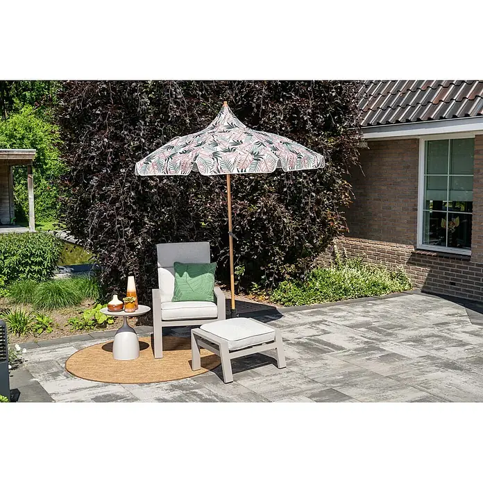 Garden Impressions Marktschirm rund Aloha - Rosa/Blättermotiv, Durchmesser Bespannung: 200 cm - Eine Outdoor-Lounge-Sessel, Hocker und Beistelltisch auf einer Terrasse, beschattet von einem gemusterten Sonnenschirm mit rosa und grünen Blättern.