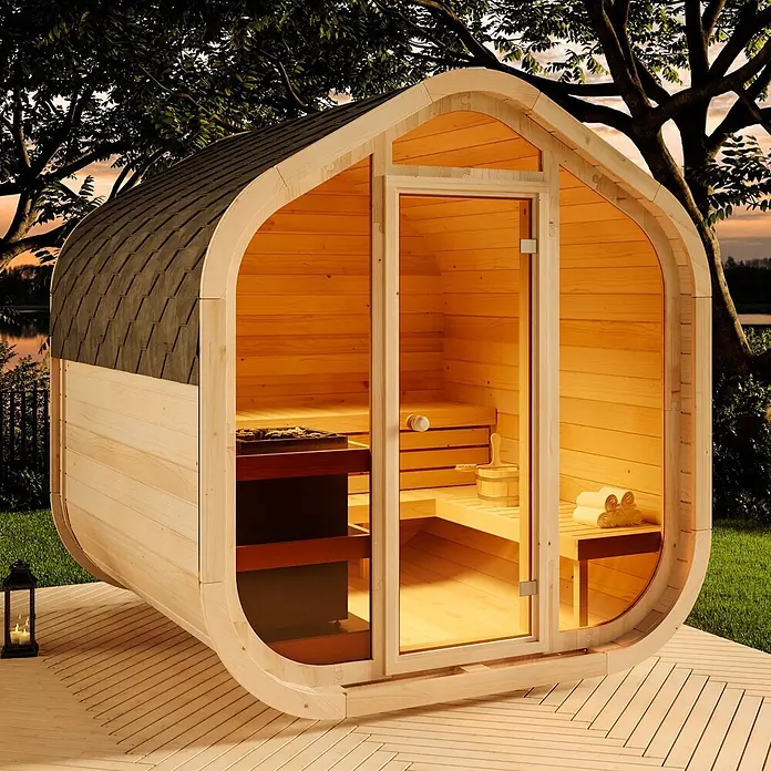 FinnTherm Fasssauna ScandiCube Wave Comfortissimo - Holz, L x B x H: 236 x 237 x 249 cm - Outdoor-Fasssauna aus hellem Holz mit dunklem Schindeldach und Glastür, ausgestattet mit Innenbänken und Saunaofen auf einer Terrasse.