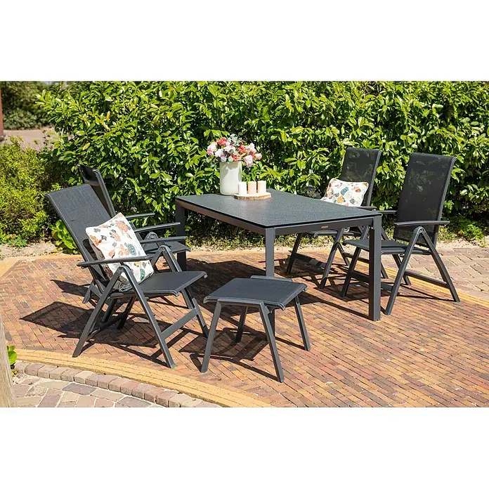 Garden Impressions Garten-Positionssessel Gala - Aluminium, Klappbar, Schwarz/Anthrazit, B x T x H: 61 x 75 x 108 cm - Dunkelgraues Terrassen-Essgruppe mit Tisch, vier Stühlen und einem kleinen Hocker auf einer Ziegelterrasse, dekoriert mit Kissen und Blumen.