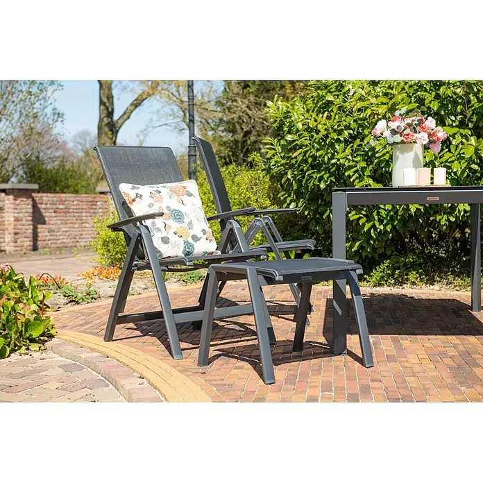 Garden Impressions Garten-Positionssessel Gala - Aluminium, Klappbar, Schwarz/Anthrazit, B x T x H: 61 x 75 x 108 cm - Dunkelgraues Garten-Loungeset mit Stühlen, Fußhocker und Tisch auf einer Ziegelterrasse. Ein Stuhl hat ein Blumenkissen.